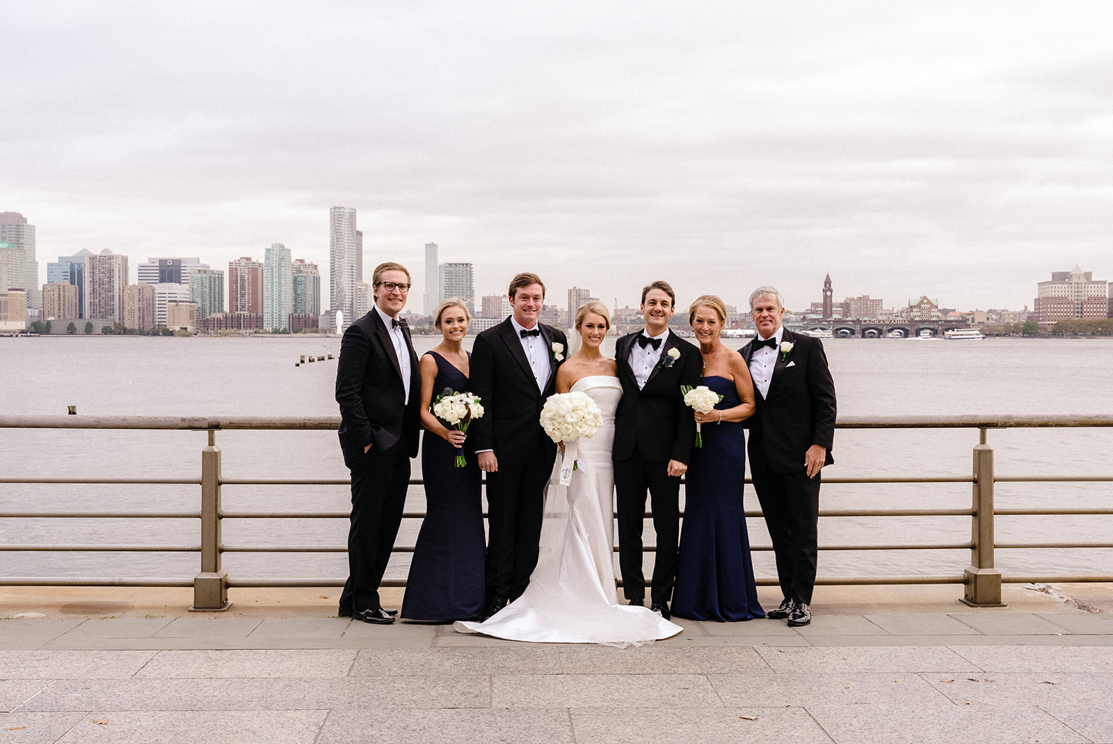 Top 4 Luxury Wedding Venues in New York. Couple with bridal party posing with view of the sea and city behind them.