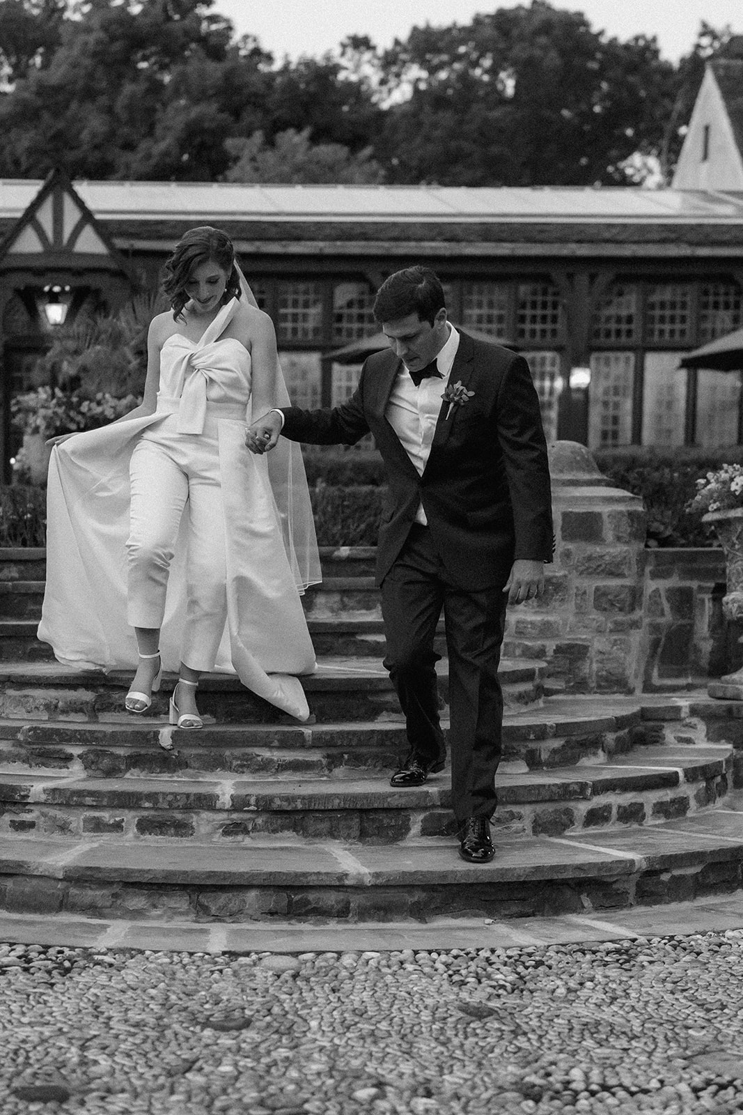 Black and white photo of couple descending the stairs while holding hands, shot by For Fearless Hearts