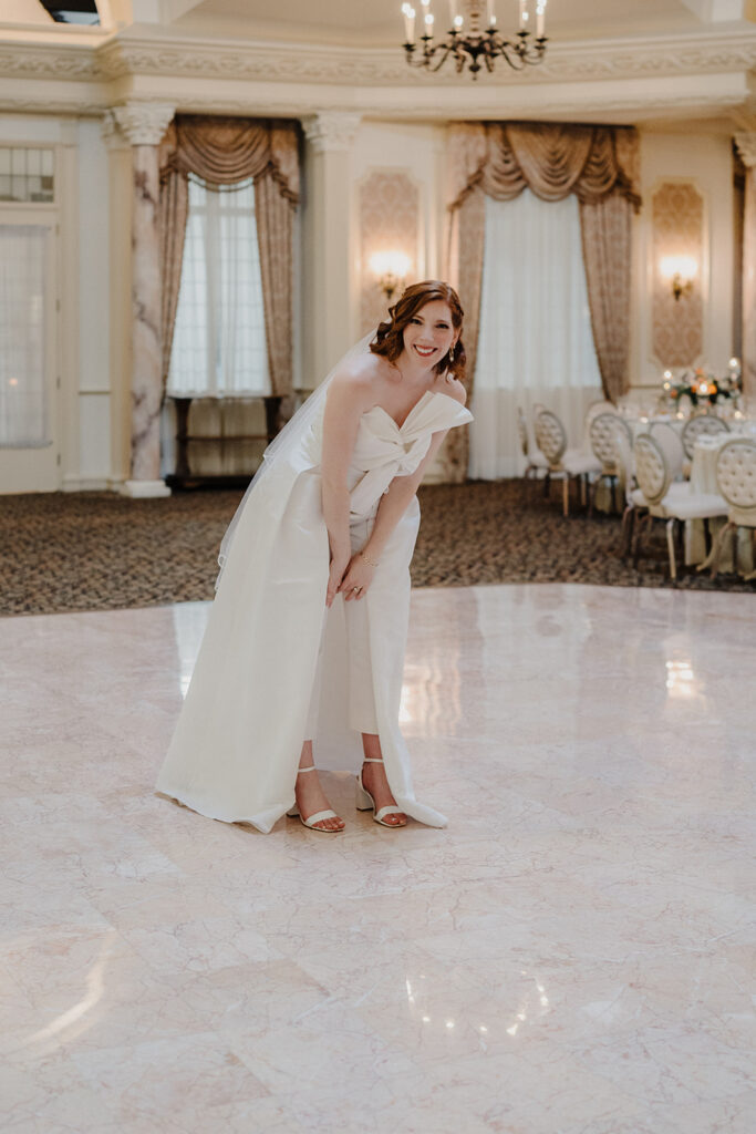 Bride candidly posing and smiling at the camera in the middle of the ballroom, captured by For Fearless Hearts