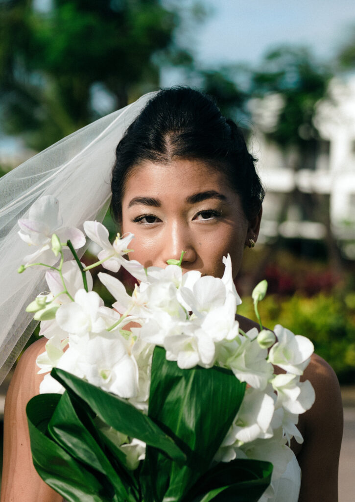 Portrait shot of bride holding flower in front of her, taken by For Fearless Hearts